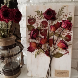 This image shows dried red rose flower bouquet in a frame and in a vase